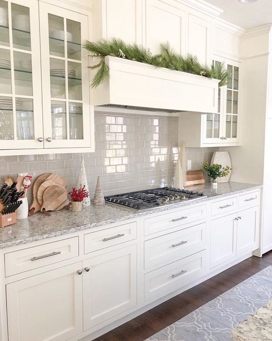 a white kitchen with shaker style cabinets, a grey tile backsplash, grey granite countertops and built-in appliances