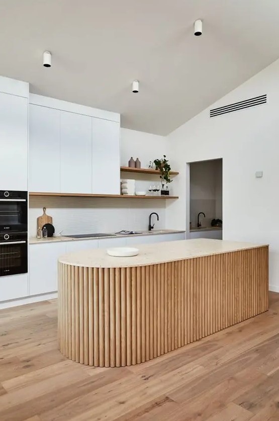 a white minimalist kitchen with a neutral stone countertop, a curved fluted kitchen island and open shelves