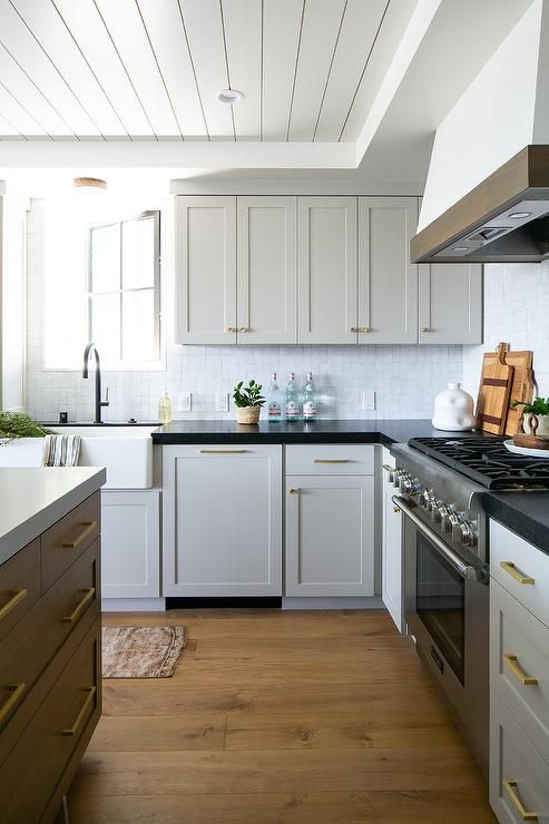 a white shaker style kitchen with black soapstone cabinets, a stained kitchen island and neutral countertops, black fixtures