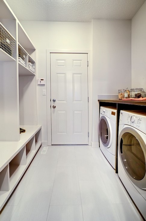 an all-white mudroom laundry with an open storage unit, a washing machine and a dryer and nothing else