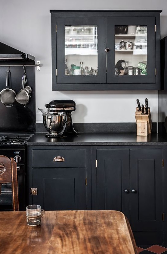 an elegant graphite grey kitchen with black countertops, elegant brass touches and black granite countertops wows