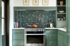 a stylish green kitchen with a floral wallpaper backsplash