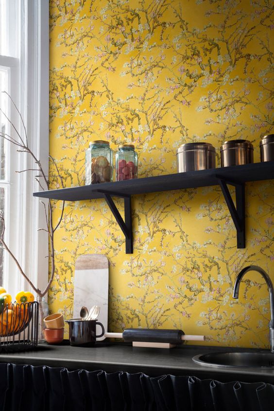 a black kitchen accented with bold yellow floral wallpaper stands out even more in the backdrop of such wallpaper