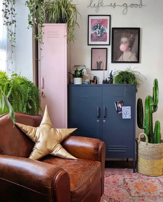 a bright eclectic space with a pink and navy locker, a leather chair, a bright printed rug, a gallery wall and potted greenery