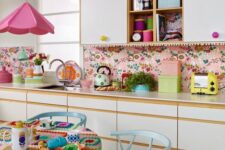 05 a bright retro kitchen with white flat panel cabinets, a bright pink wallpaper backsplash, a bright pink pendant lamp and pastel blue dining furniture