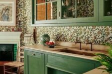 06 a green kitchen with butcherblock countertops, a bright floral wallpaper backsplash and glass cabinets is a stylish vintage-infused space