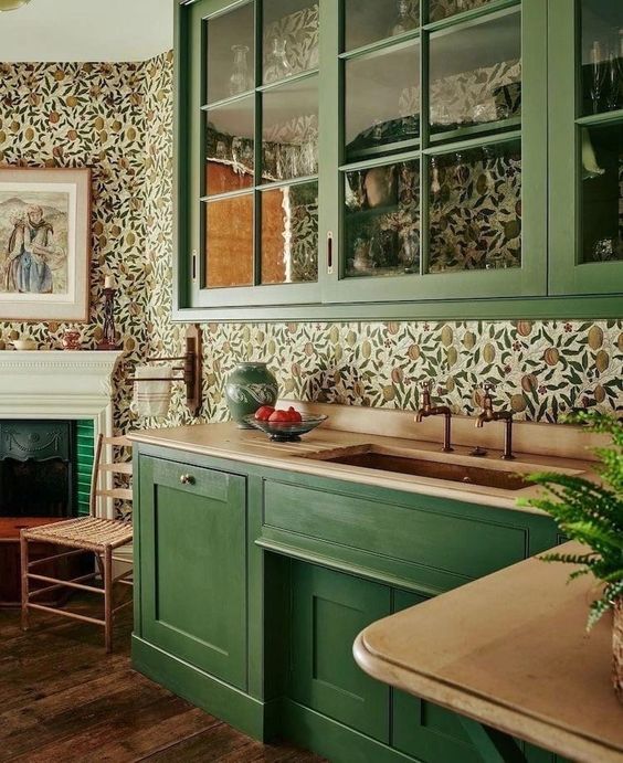 a green kitchen with butcherblock countertops, a bright floral wallpaper backsplash and glass cabinets is a stylish vintage-infused space