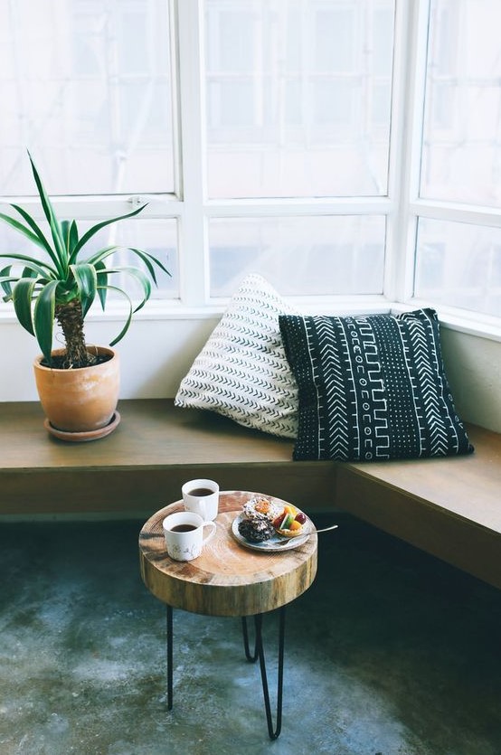 a mid-century modern corner space with a wall-mounted bench with printed pillows, a tree slice side table on hairpin legs is cool