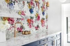 10 a navy and white kitchen with shaker cabinets, white marble countertops, a bright floral wallpaper wall and open shelves plus brass touches