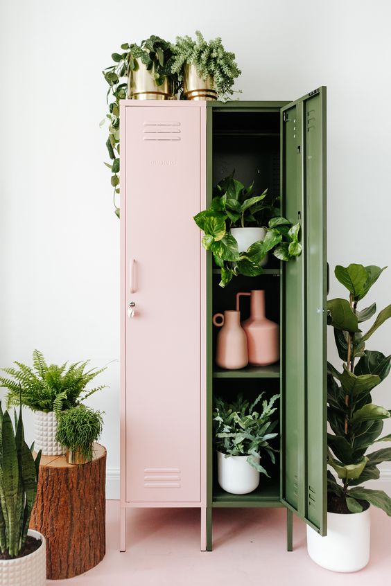 a pink and green locker as a plant stand and a storage unit, with lots of greenery inside, on top and around it