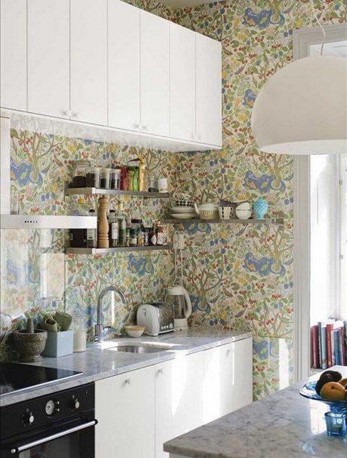 a neutral kitchen with flat panel cabinets, bright floral wallpaper that stands out a lot and a kitchen island with a lamp over it
