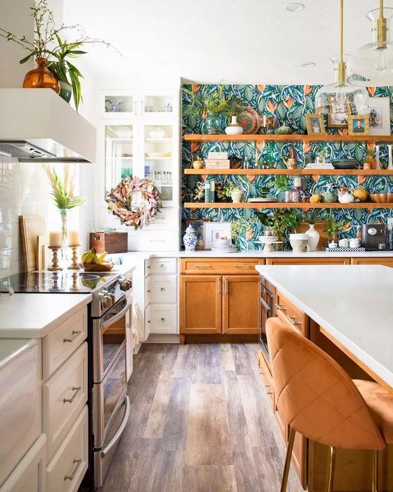 a beautiful white and stained kitchen with shaker cabinets, open shelving and glass front cabinets, white stone countertops and floral wallpaper as backing for the shelves