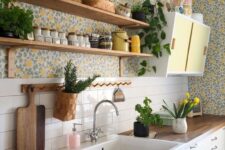 20 a bold cottage kitchen with white beadboard cabinets, colorful floral wallpaper, open shelving, a small yellow cabinet and butcherblock countertops