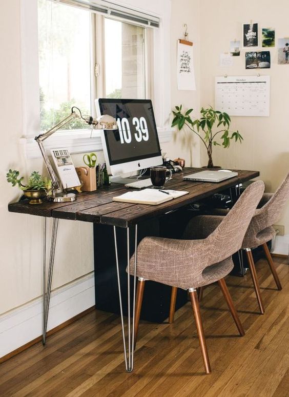a dark-stained shared desk with hairpin legs and grey chairs, potted plants, a table lamp is a great space