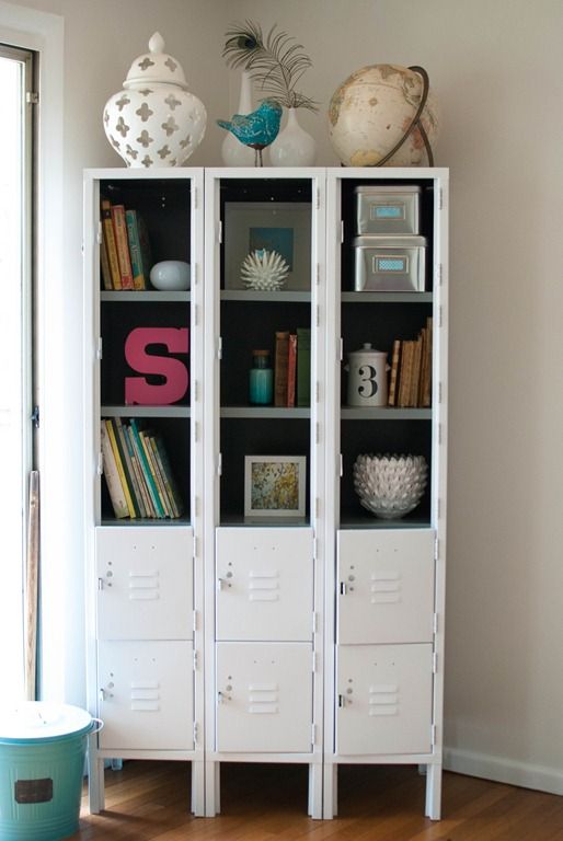 a set of white lockers turned into a bookcase with books and art on display is a cool idea for a modern space