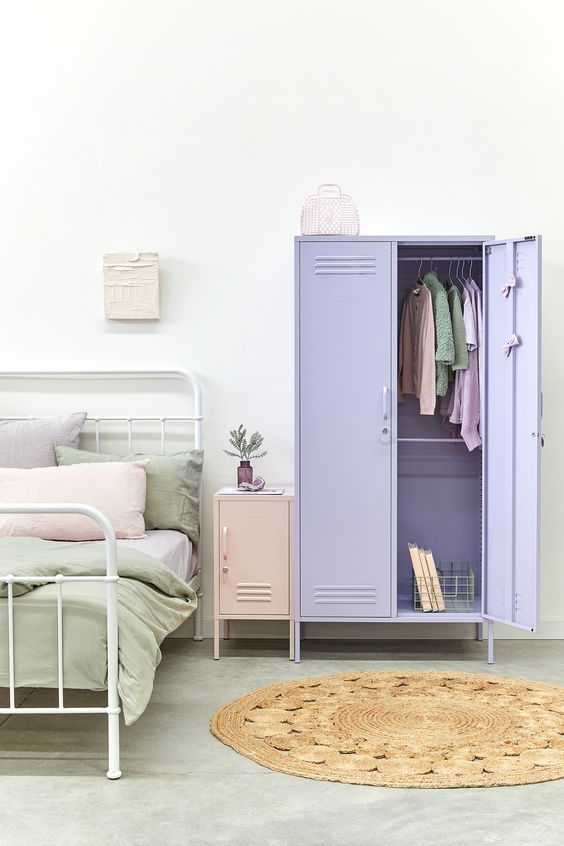 a pastel bedroom with a white metal bed, pastel bedding, a blush locker nightstand and a lilac locker as a wardrobe is a lovely space