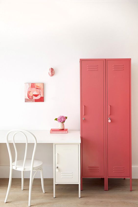 a cool home office with a creamy desk and a locker for storage, coral lockers for storage and some pink and coral art