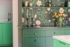 27 a dark green kitchen with a bold green kitchen island, dark floral wallpaper in the back of a buffet and beautiful decor