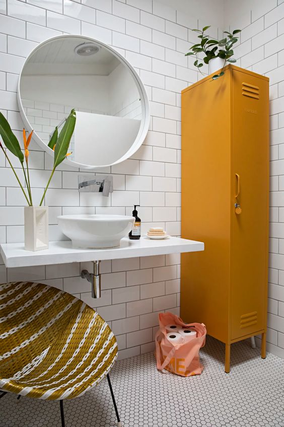 a catchy bathroom with white subway and hex tiles, a wall-mounted vanity and sink, a mustard locker and a woven round chair
