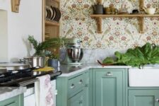 29 a green farmhouse kitchen with shaker cabinets, white stone countertops, delicate floral wallpaper, open shelves and potted greenery