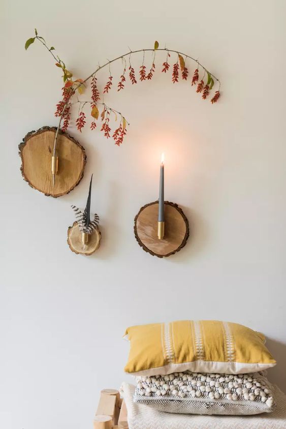 a wood slice home wall art with a branch, some feathers and a candle will fit a boho or eclectic space easily