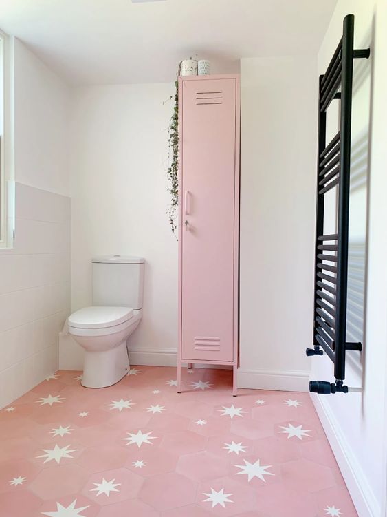 a cool bathroom with a pink star print floor, a pink skinny locker for storing stuff, a black radiator is a lovely space