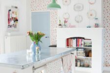30 a kitchen with bright floral wallpaper, a non-working fireplace with book storage, a kitchen island and green pendant lamps
