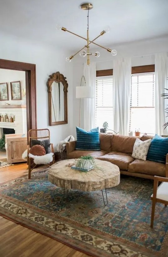 a mid-century modern space with a large leather sofa, a tree slice table, rattan chairs and a creative chandelier