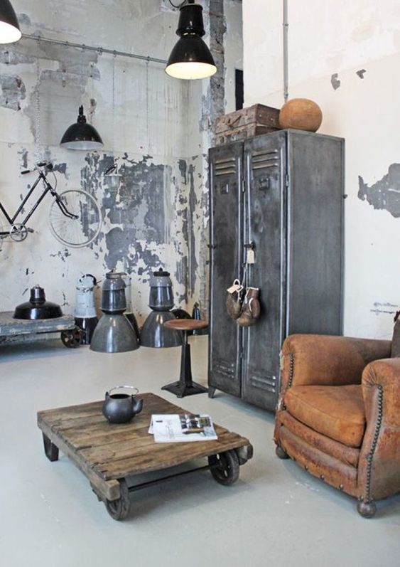 a shabby chic industrial interior with metal lockers, a leather chair, a coffee table on casters, metal pendant lamps and a bike on the wall