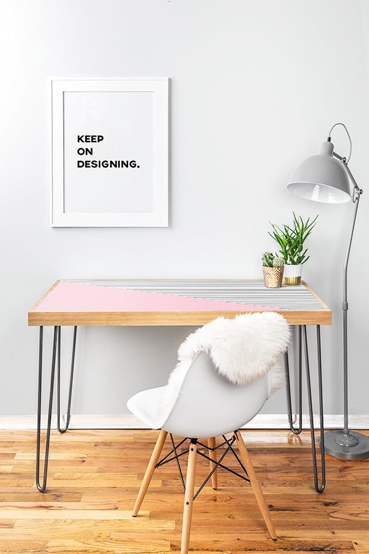 a pink and stripe color block desk with hairpin legs, a white chair, a grey floor lamp and an artwork  for working