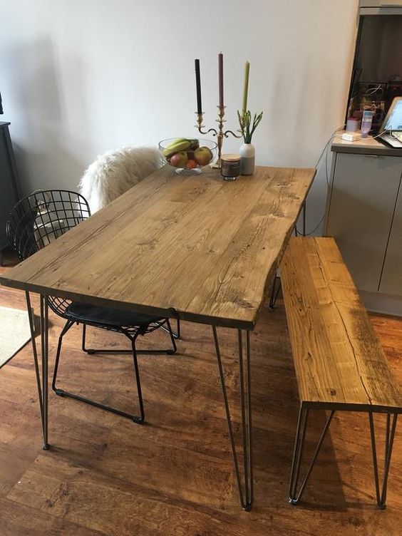 a rustic dining space with a living edge hairpin leg table and a matching bench, black metal chairs, candles and some decor