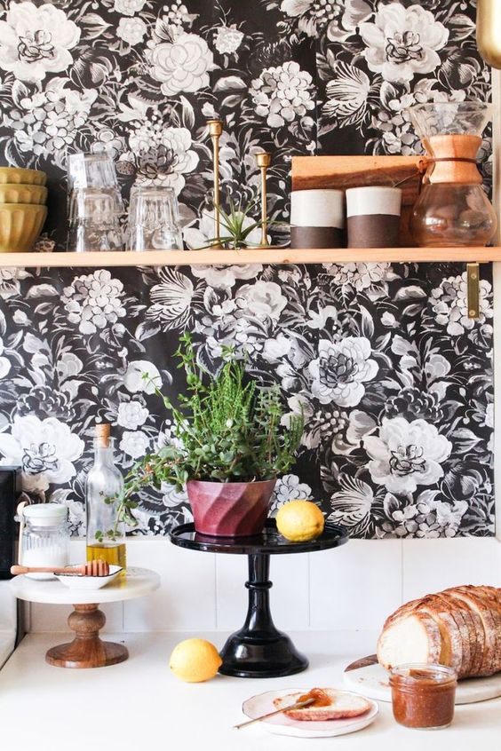 a white kitchen accented with elegant black and white floral wallpaper, white square tiles and with an open shelf for storage and display