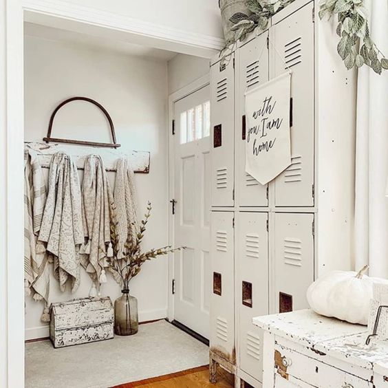 a creamy farmhouse space with a series of lockers, a white dresser, pumpkins, greenery and towels is cool