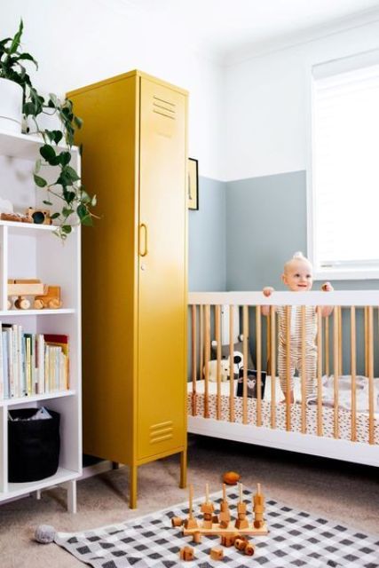 a mid-century modern nursery with a white shelving unit, a mustard locker for storage, a white and stained crib, a printed rug