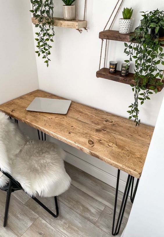 a small rustic desk with hairpin legs in the corner, a chair with faux fur, suspended shelves with potted greenery