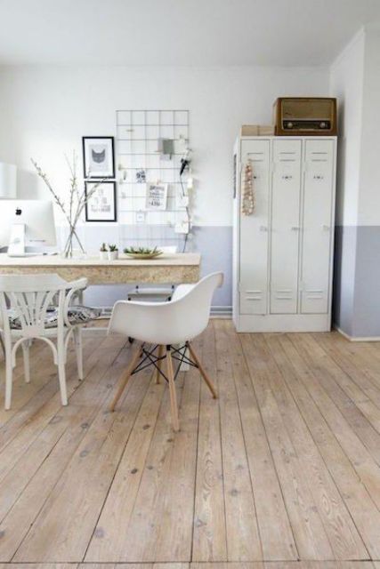 a Scandinavian home office with creamy lockers, a large desk, white chairs, a grid memo board and some art