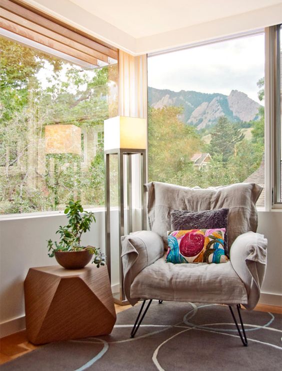 a comfy grey chair on hairpin legs and a geometric sculptural faceted side table for a cozy nook