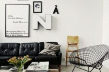a Scandinavian living room with a black leather sofa, a wooden table on casters and a metal wire chair