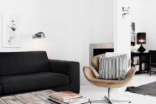 a Scandinavian living room with a black sofa, an amber leather chair, a low industrial coffee table and some books