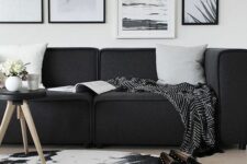 a Scandinavian living room with a low black sofa, a black and white gallery wall, a printed rug and a black floor lamp