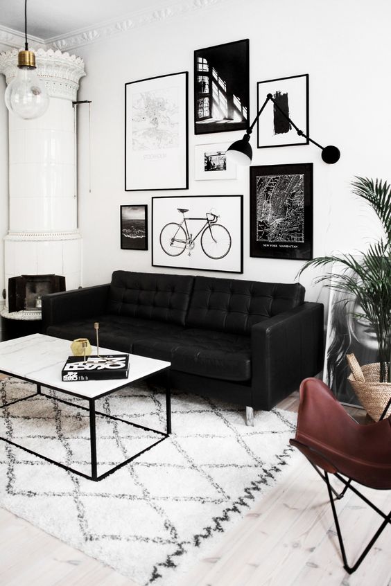 a Scandinavian living room with a white hearth, a black leather sofa, a leather butterfly chair, a coffee table and a gallery wlal