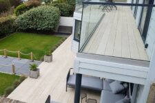 a balcony and a terrace clad with smoked oak decking, with grey upholstered furniture and potted greenery plus a sea view