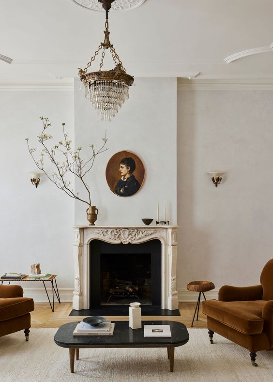 a beautiful French living room with an ornated French fireplace, brown seating furniture, a low coffee table, a crystal chandelier and some more tables