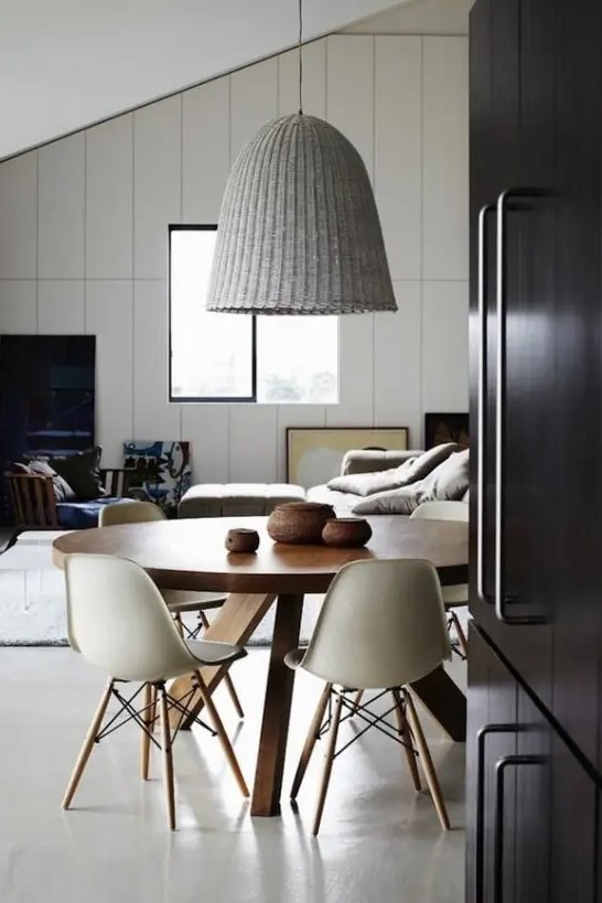 a beautiful Nordic dining space with a stained round table, white Eames chairs, a woven pendant lamp is a very cool and laconic space to have meals