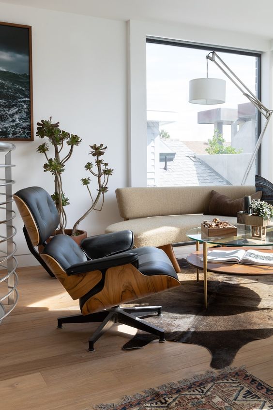 a beautiful contemporary living room with a curved sofa, a black Eames lounger, a tiered coffee table, a floor lamp