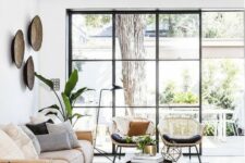 a beautiful living room with a glazed wall, a low leather sofa, a low coffee table, rattan chairs and potted plants