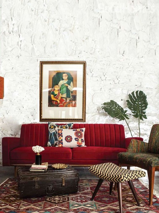 a beautiful living room with catchy walls, a deep red sofa, printed furniture and a rug and a vintage suitcase for storage