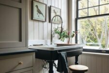 a beautiful vintage space with tan beadboard and cabinetry, black and white tiles, a black French double-hung window, a sink on a black stand