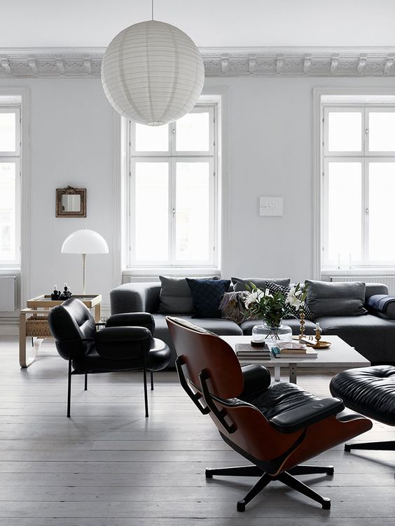 a black and white Scandinavian living room with plenty of natural light, black seating furniture, a white coffee table and a white paper lamp