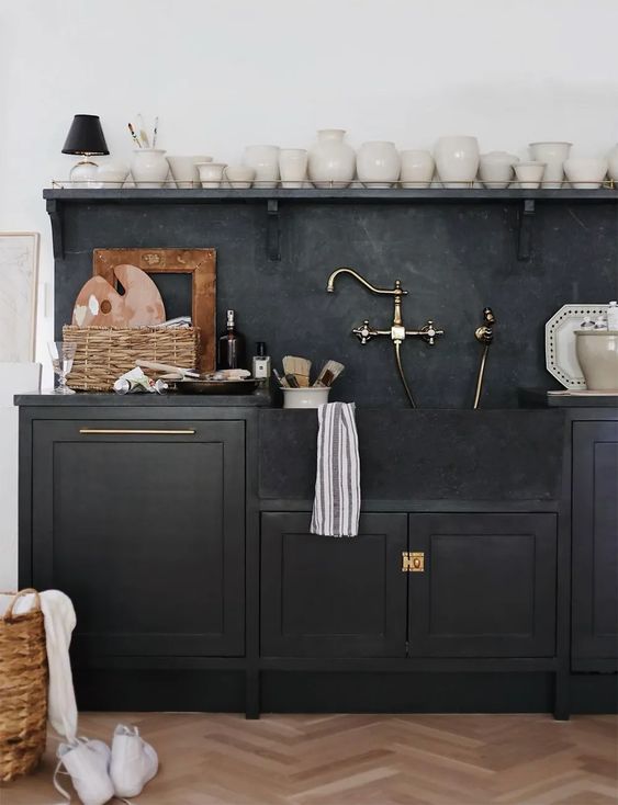 a black shaker style kitchen with black soapstone countertops and a backsplash, an open shelf to display beautiful vases